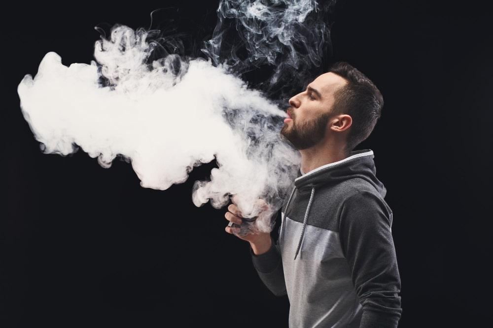 man with vaping mod exhaling steam black studio background bearded guy smoking e cigarette quit tobacco vapor alternative nicotine free smoking concept copy space min